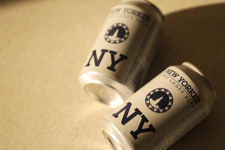 TERNOPIL, UKRAINE - JULY 18, 2022 Two cans of New Yorker fine lager beer with original logo and design on brown retro background surfaceのeditorial素材