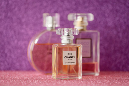 TERNOPIL, UKRAINE - SEPTEMBER 2, 2022 Chanel Number 5 Eau Premiere famous worldwide french perfume bottle among other perfumes on shiny glitter background in purple and pink colorsのeditorial素材