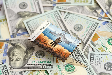 TERNOPIL, UKRAINE - SEPTEMBER 2, 2022 Famous Ukrainian postmark with russian warship and ukrainian soldier as wooden souvenir on huge amount of US dollar billsのeditorial素材