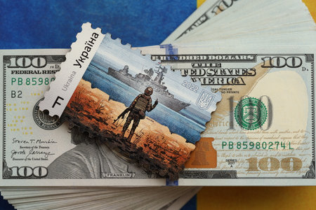 TERNOPIL, UKRAINE - SEPTEMBER 2, 2022 Famous Ukrainian postmark with russian warship and ukrainian soldier as wooden souvenir on huge amount of US dollar billsのeditorial素材