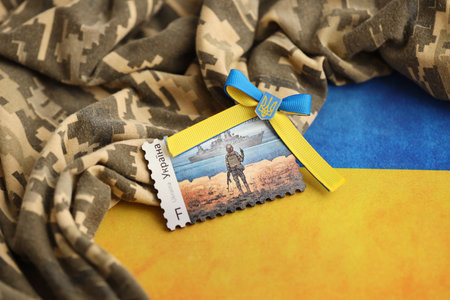 TERNOPIL, UKRAINE - SEPTEMBER 2, 2022 Famous Ukrainian postmark with russian warship and ukrainian soldier as wooden souvenir on army camouflage uniform cloth and national flagのeditorial素材