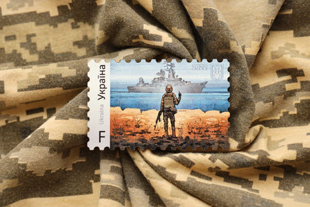 TERNOPIL, UKRAINE - SEPTEMBER 2, 2022 Famous Ukrainian postmark with russian warship and ukrainian soldier as wooden souvenir on army camouflage uniform clothのeditorial素材