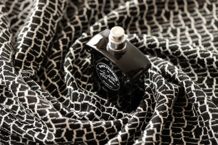 TERNOPIL, UKRAINE - SEPTEMBER 2, 2022 Black Perfecto La Petite Robe Noire by Guerlain perfume bottle on dark plaid in monochrome colorsのeditorial素材
