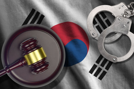 South Korea flag with judge mallet and handcuffs in dark room. Concept of criminal and punishment, background for guilty topicsの写真素材
