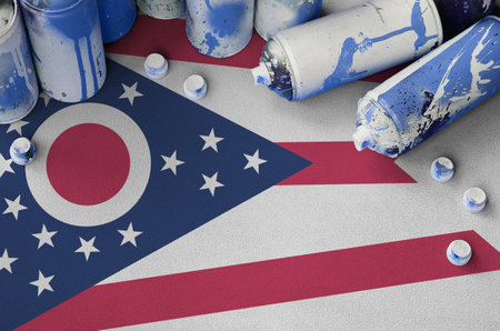 Ohio US state flag and few used aerosol spray cans for graffiti painting. Street art culture concept, vandalism problemsの写真素材