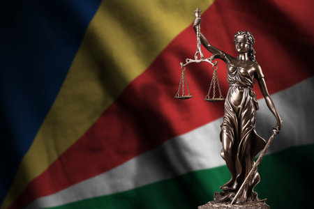 Seychelles flag with statue of lady justice and judicial scales in dark room. Concept of judgment and punishment, background for jury topicsの写真素材