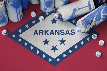 Arkansas US state flag and few used aerosol spray cans for graffiti painting. Street art culture concept, vandalism problemsの写真素材