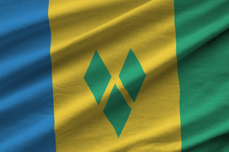 Saint Vincent and the Grenadines flag with big folds waving close up under the studio light indoors. The official symbols and colors in fabric bannerの写真素材