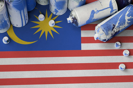 Malaysia flag and few used aerosol spray cans for graffiti painting. Street art culture concept, vandalism problemsの写真素材