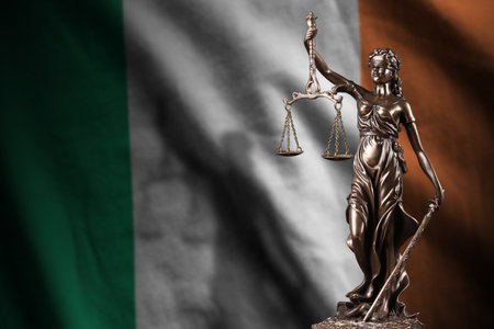 Ireland flag with statue of lady justice and judicial scales in dark room. Concept of judgement and punishment, background for jury topicsの写真素材