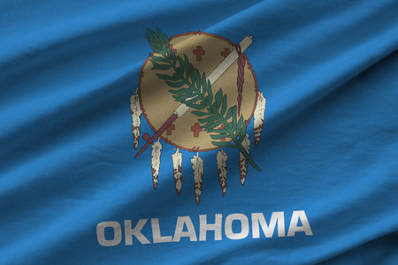 Oklahoma US state flag with big folds waving close up under the studio light indoors. The official symbols and colors in fabric bannerの写真素材