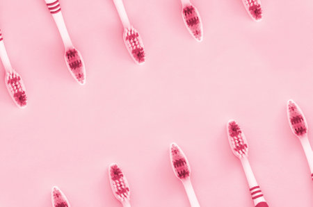A lot of toothbrushes lie on a pastel blue background. Top view, flat lay. Minimal concept. Image toned in Viva Magenta, color of the 2023 yearの写真素材