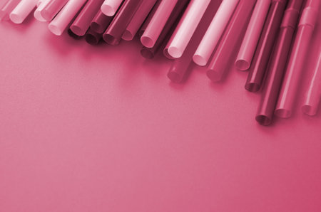 Many colorful straws for drinks lies on a bright orange background surface Image toned in Viva Magenta, color of the 2023 yearの写真素材