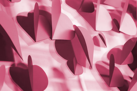 A lot of pink, purple and white paper hearts decorate the window of the house Image toned in Viva...