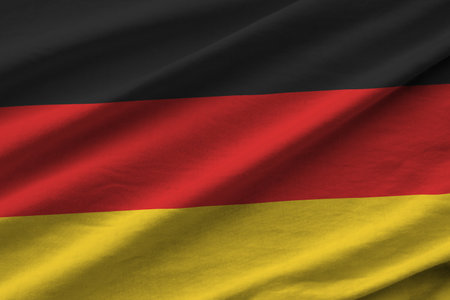 Germany flag with big folds waving close up under the studio light indoors. The official symbols and...