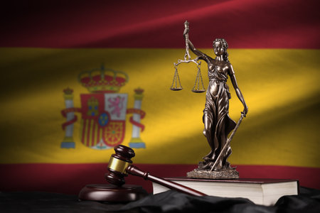 Spain flag with statue of lady justice, constitution and judge hammer on black drapery. Concept of judgement and punishmentの写真素材