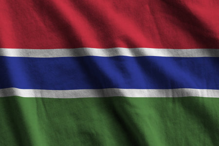 Gambia flag with big folds waving close up under the studio light indoors. The official symbols and colors in fabric bannerの写真素材