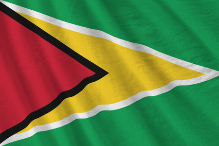 Guyana flag with big folds waving close up under the studio light indoors. The official symbols and...