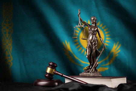 Kazakhstan flag with statue of lady justice, constitution and judge hammer on black drapery. Concept of judgement and punishmentの写真素材