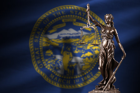 Nebraska US state flag with statue of lady justice and judicial scales in dark room. Concept of judgement and punishment, background for jury topicsの写真素材