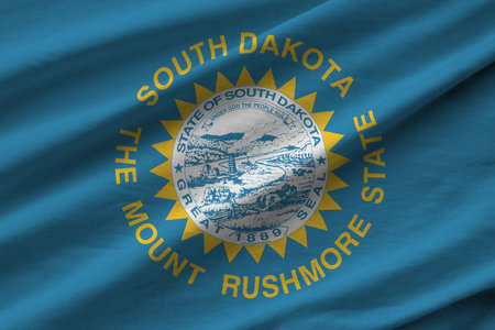 South Dakota US state flag with big folds waving close up under the studio light indoors. The official symbols and colors in fabric bannerの写真素材