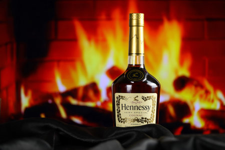 KYIV, UKRAINE - MAY 4, 2022 Hennessy Very Special original alcohol bottle on wooden table with red fireplace on background. Elite alcohol productionのeditorial素材