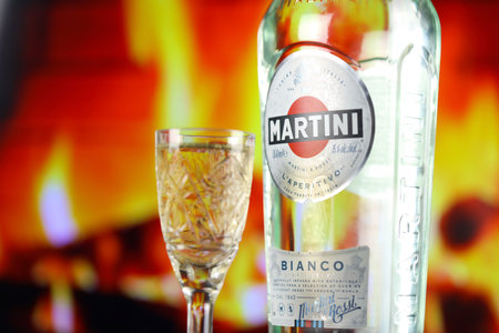 KYIV, UKRAINE - MAY 4, 2022 Vermouth Martini original alcohol bottle on wooden table with red fireplace on background. Elite alcohol productionのeditorial素材
