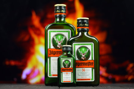 KYIV, UKRAINE - MAY 4, 2022 Jagermeister original alcohol bottle on wooden table with red fireplace on background. Elite alcohol productionのeditorial素材
