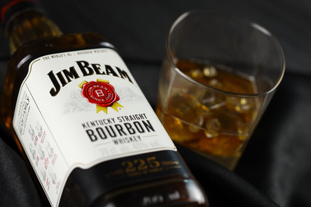 KYIV, UKRAINE - MAY 4, 2022 Jim Beam original alcohol bottle on wooden table with black fabric on background. Elite alcohol productionのeditorial素材