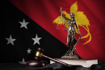 Papua New Guinea flag with statue of lady justice, constitution and judge hammer on black drapery. Concept of judgement and punishmentの写真素材