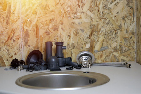 Plumbers tools and water tap ready for installation near sink on countertop in kitchen. Connections for the installation of the water faucet for the kitchen sinkの写真素材