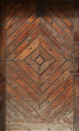 Old ancient wooden door texture in european medieval style. The detailed texture of closed brown aged door from weathered and stained wooden planks and boardsの写真素材