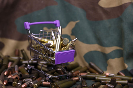 Rifle cartridges in small shopping cart. Big caliber ammo cartridges with a small shopping basket close upの写真素材
