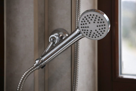 Silvery shower in modern hotel bathroom with natural light from window