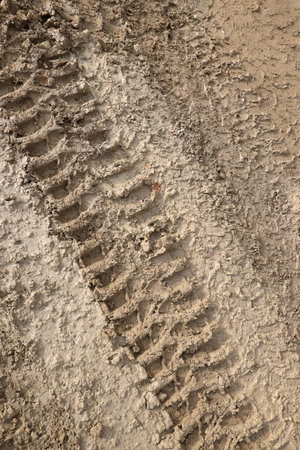 Wheel track on mud. Traces of a tractor or heavy off-road car on brown mud in a wet meadowの写真素材
