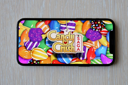 Candy Crush Saga mobile iOS game on iPhone 15 smartphone screen on wooden table during mobile gameplay. Mobile gaming and entertainment on portable deviceのeditorial素材