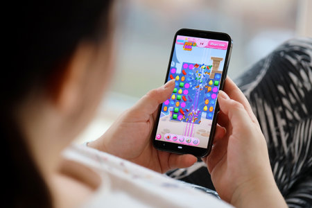 Candy Crush Saga mobile iOS game on iPhone 15 smartphone screen in female hands during mobile...