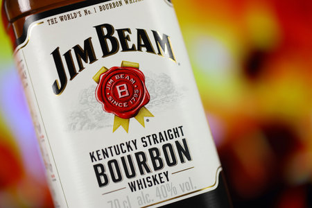 KYIV, UKRAINE - MAY 4, 2022 Jim Beam original alcohol bottle on wooden table with red fireplace on background. Elite alcohol productionのeditorial素材