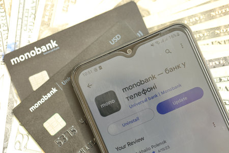 KYIV, UKRAINE - JULY 7, 2023 Monobank black banking plastic cards with money on tableのeditorial素材