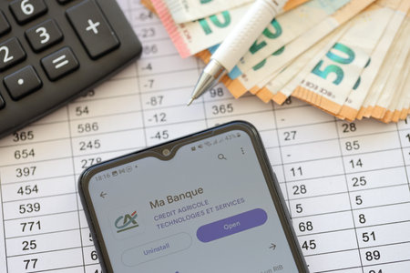 TERNOPIL, UKRAINE - AUGUST 3, 2023 Credit Agricole CA application on screen on modern smartphone and many bills of european euro currencyのeditorial素材