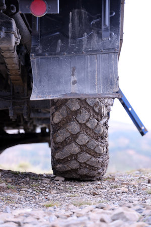Wheel closeup in a countryside landscape with a mud road. Off-road 4x4 suv automobile with ditry body after drive in muddy road areaの写真素材