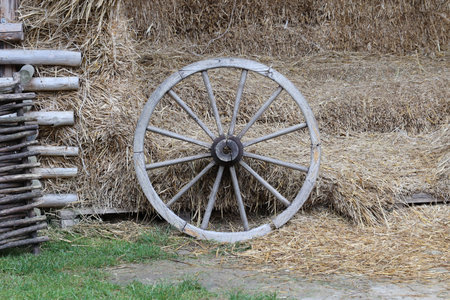 Place with stacks of hay cubes and rustic wooden wheels of old cart close upの写真素材