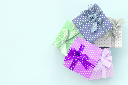 Pile of a small colored gift boxes with ribbons lies on a violet background. Minimalism flat lay top...
