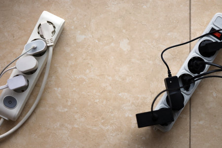 Overloaded power boards. Power strips with different electrical plugs on white floor. Concept of risk danger overloaded current electricalの写真素材