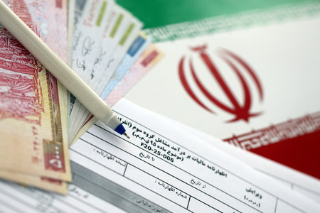 Iranian annual income tax return form F20-25-006 ready to fill on table with pen and iranian money...