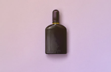 Dark purple perfume bottle with golden ribbon on pastel paper background. Trendy fragrance designの写真素材