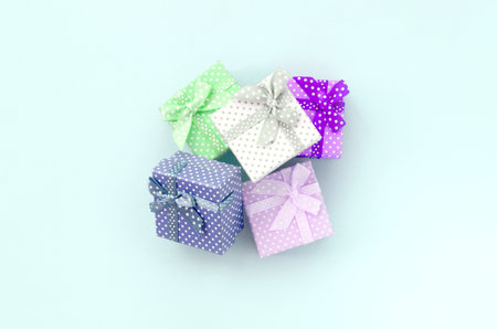 Pile of a small colored gift boxes with ribbons lies on a violet background. Minimalism flat lay top...