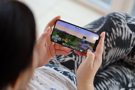 Minecraft mobile iOS game on iPhone 15 smartphone screen in female hands during mobile gameplay. Mobile gaming and entertainment on portable deviceのeditorial素材