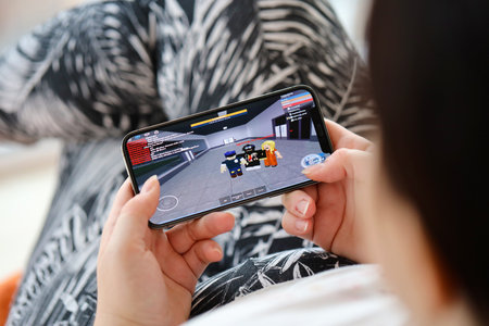 Roblox mobile iOS game on iPhone 15 smartphone screen in female hands during mobile gameplay. Mobile gaming and entertainment on portable deviceのeditorial素材