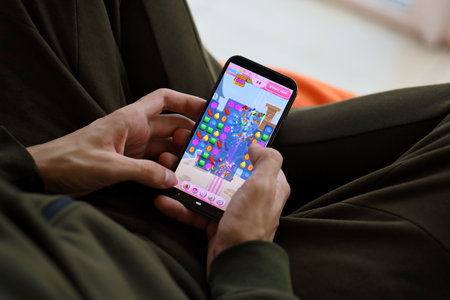 Candy Crush Saga mobile iOS game on iPhone 15 smartphone screen in male hands during mobile...